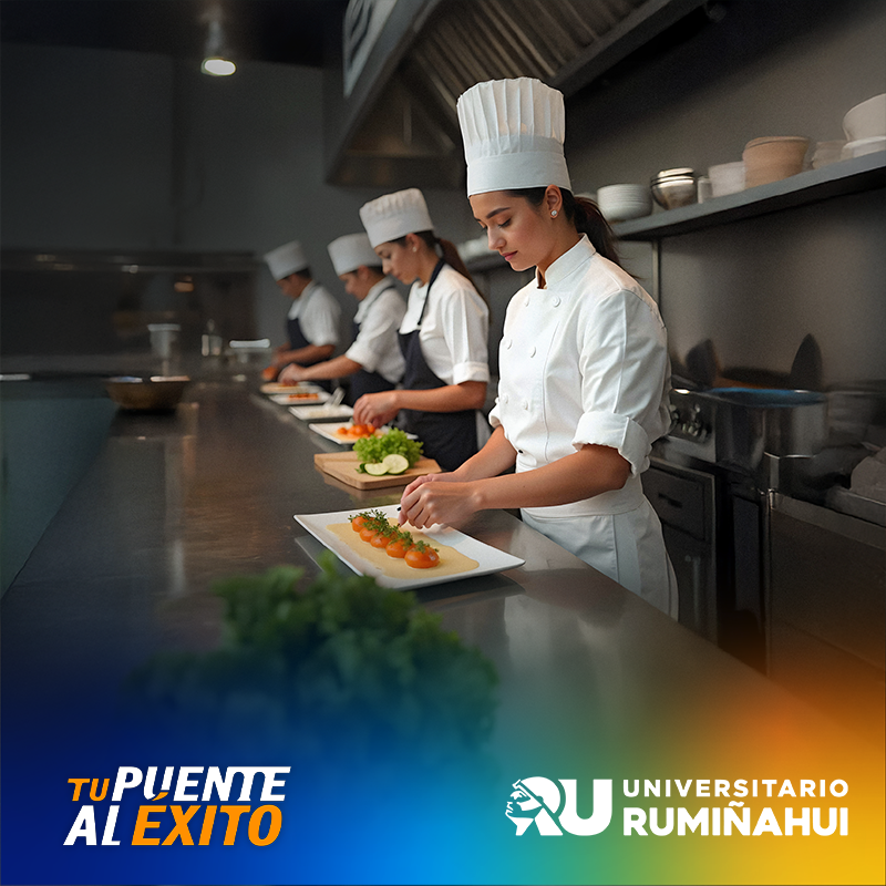 Female chef student in white uniform and hat plates orange hors d'oeuvres on a white plate in a stainless-steel kitchen with teammates in the background.